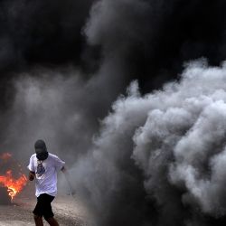 Manifestantes palestinos se cubren tras el humo durante los enfrentamientos con las fuerzas israelíes tras una protesta contra una marcha de colonos israelíes hacia el asentamiento salvaje de Homesh, en el pueblo de Burqa, en el norte de la Cisjordania ocupada. | Foto:JAAFAR ASHTIYEH / AFP