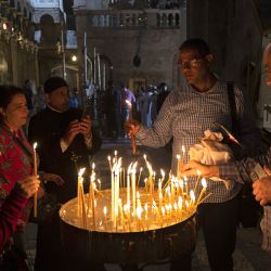 Peregrinos cristianos encienden velas mientras visitan la Iglesia del Santo Sepulcro en la Ciudad Vieja de Jerusalén. | Foto:MENAHEM KAHANA / AFP