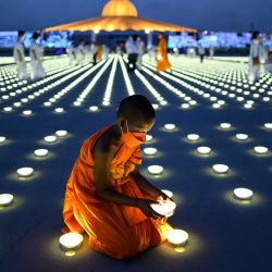 Un joven monje budista coloca una luz LED como parte de las celebraciones del Día de la Tierra en el templo budista Wat Dhammakaya en la provincia de Pathum Thani, al norte de Bangkok, Tailandia. | Foto:MANAN VATSYAYANA / AFP