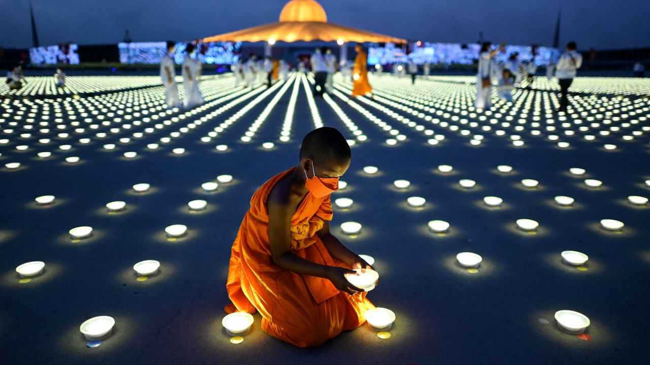 Un joven monje budista coloca una luz LED como parte de las celebraciones del Día de la Tierra en el templo budista Wat Dhammakaya en la provincia de Pathum Thani, al norte de Bangkok, Tailandia. | Foto:MANAN VATSYAYANA / AFP