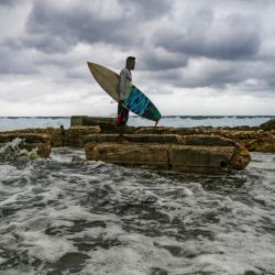 El surfista cubano Alexei Martínez mira las olas en la costa de en La Habana. | Foto:YAMIL LAGE / AFP