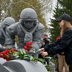 Un grupo de personas deposita flores en el monumento de Chernóbil para rendir homenaje a los bomberos que murieron durante el desastre de 1986 en la central nuclear de Chernóbil. | Foto:SERGEI SUPINSKY / AFP