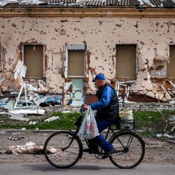 Un hombre pasa con su bicicleta por delante de una casa destruida en el pueblo de Derhachi, al norte de Kharkiv, en el este de Ucrania, en medio de la invasión rusa de Ucrania. | Foto:DIMITAR DILKOFF / AFP