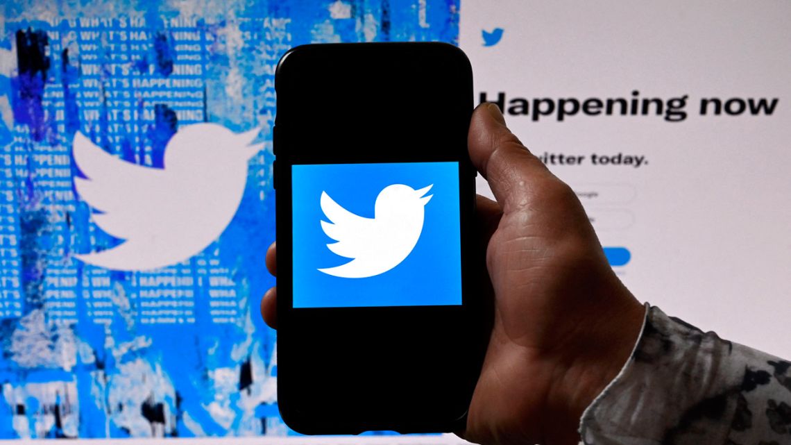 A phone screen displays the Twitter logo on a Twitter page background.