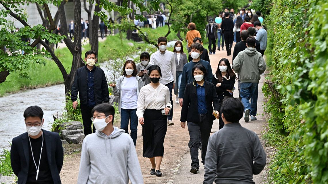 People wearing face masks walk along the Cheonggye stream in Seoul on April 29, 2022.