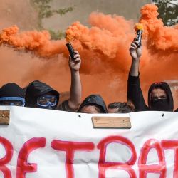 Los manifestantes sostienen bombas de humo y una pancarta en la que se lee "jubilación a los 20 años" mientras participan en una manifestación en Nantes, al oeste de Francia. | Foto:SALOM-GOMIS / AFP