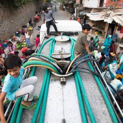 Los residentes utilizan mangueras para recoger agua potable de un camión cisterna durante un caluroso día de verano en Nueva Delhi, India. | Foto:XAVIER GALIANA / AFP