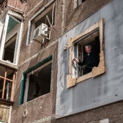 Un hombre sostiene un smartphone desde la ventana rota de un apartamento dañado por la explosión de un misil en Kramatorsk, en el este de Ucrania, en medio de la invasión rusa de Ucrania. | Foto:YASUYOSHI CHIBA / AFP