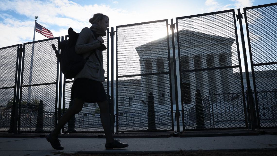 A pedestrian walks past non-scalable fencing after it was installed overnight around the U.S. Supreme Court Building amid ongoing abortion-rights demonstrations, May 5, 2022.