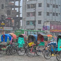Conductores de rickshaw se refugian durante una fuerte lluvia en Dhaka, Bangladesh. | Foto:MUNIR UZ ZAMAN / AFP