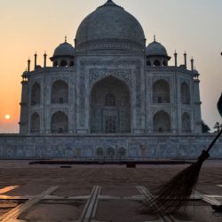 Un trabajador barre el suelo del Taj Mahal al amanecer en Agra, India. | Foto:PAWAN SHARMA / AFP