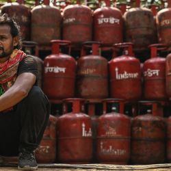 Un trabajador se sienta junto a las bombonas de GLP (gas licuado de petróleo) cargadas en un camión cerca de un depósito en Nueva Delhi, India. | Foto:Sajjad Hussain / AFP