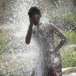 Un hombre se refresca mientras el agua salpica de una tubería de agua rota durante un caluroso día de verano en Karachi. Asif HASSAN / AFP | Foto:AFP
