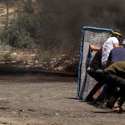 Los palestinos se refugian detrás de una barrera improvisada durante los enfrentamientos con las fuerzas israelíes luego de una manifestación contra la expropiación de tierras palestinas por parte de Israel en la aldea de Kfar Qaddum. JAAFAR ASHTIYEH / AFP | Foto:AFP