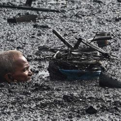 Un residente vadea las aguas de la marea alta mientras recoge los materiales reciclables de su casa quemada después de que un incendio destruyera las casas durante la noche en una zona de colonos informales cerca de la desembocadura de la bahía de Manila. | Foto:TED ALJIBE / AFP