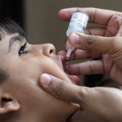 Un trabajador sanitario administra gotas de vacuna contra la polio a un niño durante una campaña de vacunación puerta a puerta en un barrio marginal de Karachi, Pakistán. | Foto:ASIF HASSAN / AFP