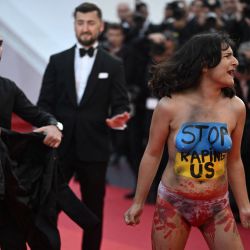 Una mujer con los colores nacionales ucranianos pintados en su cuerpo y con la leyenda "Dejad de violarnos" protesta en la alfombra roja durante la proyección de la película "Tres mil años de anhelo" durante la 75ª edición del Festival de Cine de Cannes en Cannes, sur de Francia. | Foto:LOIC VENANCE / AFP
