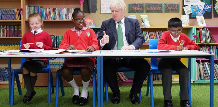 El primer ministro británico, Boris Johnson, se sienta en un pupitre con escolares durante una visita a la academia de primaria St Mary Cray, en el sureste de Londres, para ver cómo se imparten clases particulares para ayudar a los niños a ponerse al día tras la pandemia de Covid-19.