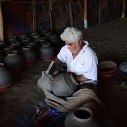 Un alfarero fabrica una vasija de arcilla para almacenar agua en un taller en las afueras de Ahmedabad, India. | Foto:SAM PANTHAKY / AFP