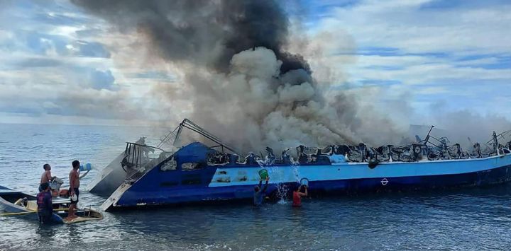 Esta foto tomada y difundida por los guardacostas filipinos muestra a personas arrojando cubos de agua sobre un ferry en llamas que se había incendiado cerca de la ciudad de Real, en la provincia de Quezón.
