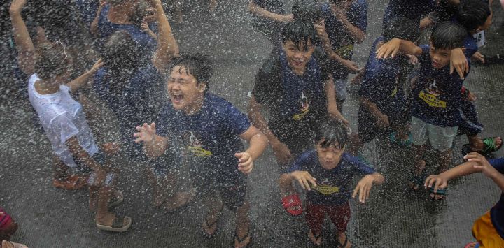 Los niños son rociados con agua mientras los devotos celebran la fiesta de Santa Rita de Cascia, patrona de las causas imposibles, en Baclaran, Manila.