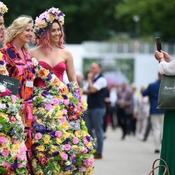 Un visitante posa para una fotografía con mujeres que llevan vestidos de temática floral en el RHS Chelsea Flower Show 2022 en Londres. | Foto:DANIEL LEAL / AFP