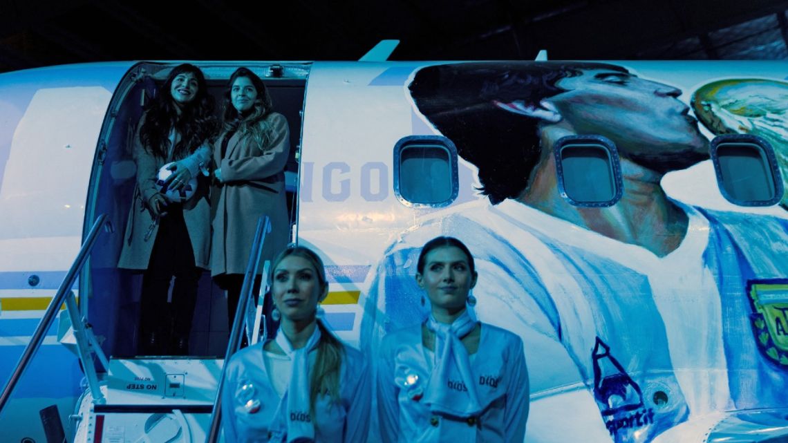 Gianinna (L, top) and Dalma Maradona (2-L, top), daughters of late Argentine football star Diego Armando Maradona, pose at an aircraft called “Tango D10S” painted with images depicting him during its presentation in Morón, Argentina, on May 25, 2022. 