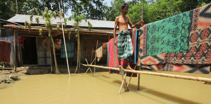 Un hombre camina por un puente peatonal improvisado de bambú frente a su casa en una zona inundada tras las fuertes lluvias en Sylhet, Bangladesh.
