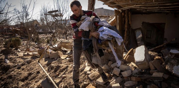 Un hombre recoge ropa de una casa dañada en la ciudad de Zhytomyr, en el norte de Ucrania.