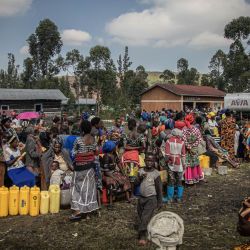 Los desplazados internos, que huyen de los recientes enfrentamientos entre los rebeldes del M23 y los soldados congoleños, hacen cola para recoger agua de un depósito de agua en Kanyarushinya, al norte de Goma, Congo. | Foto:Aubin Mukoni / AFP