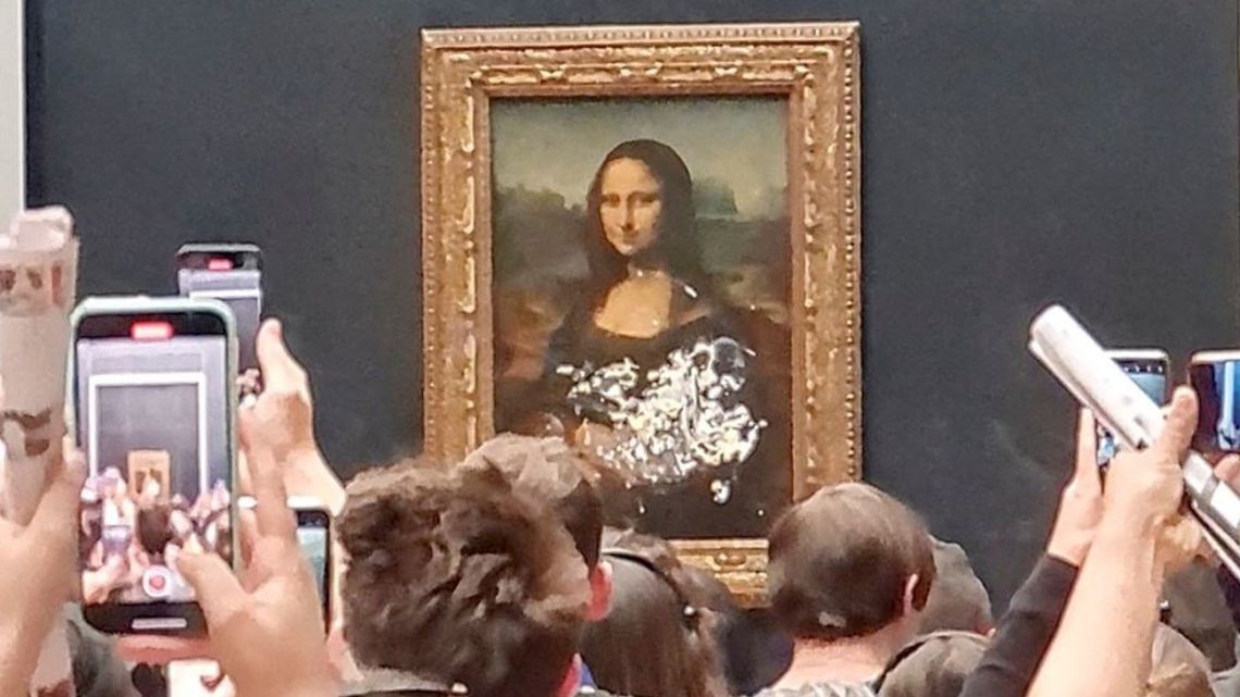 Visitors take pictures and video of the painting "Mona Lisa" after cake was smeared on the protective glass at the Louvre Museum in Paris, France, on May 29, 2022, in this screen grab obtained from a social media video. 