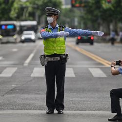 Un oficial toma una foto de otro oficial mientras controla el tráfico en el distrito Jing'an de Shanghai, tras el fin del bloqueo que mantuvo a la ciudad dos meses con restricciones de mano dura. | Foto:HECTOR RETAMAL / AFP