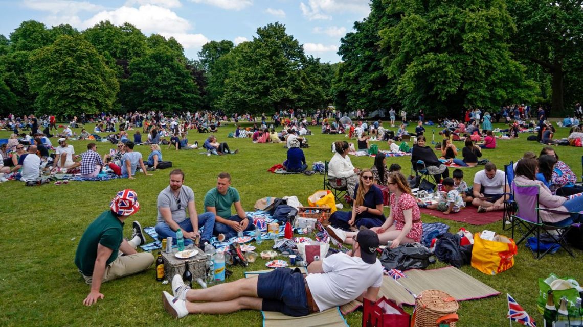 Members of the public, some with Union flag-themed memorabilia, relax in St James's Park near Buckingham Palace following the Platinum Jubilee celebrations for Queen Elizabeth II in London on June 2, 2022.