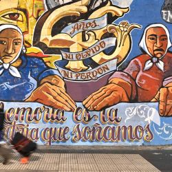 Una mujer pasa por delante de un mural que hace referencia a la organización de Derechos Humanos Madres de Plaza de Mayo durante la manifestación "Ni una menos" contra los feminicidios, cerca del edificio del Congreso en Buenos Aires. | Foto:LUIS ROBAYO / AFP