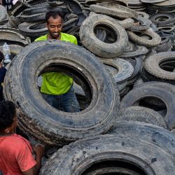 Unos trabajadores llevan neumáticos de camión usados para cortarlos y reutilizarlos en una instalación en Dhaka, Bangladesh. | Foto:MUNIR UZ ZAMAN / AFP