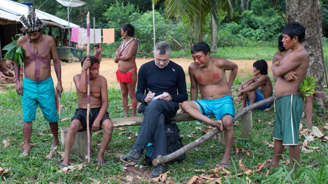 Veteran foreign correspondent Dom Phillips (centre) takes notes as he talks with indigenous people at the Aldeia Maloca Papiú, Roraima State, Brazil, on November 15, 2019. Phillips went missing while researching a book in the Brazilian Amazon's Javari Valley with respected indigenous expert Bruno Pereira. Pereira, an expert at Brazil's indigenous affairs agency, FUNAI, with deep knowledge of the region, has regularly received threats from loggers and miners trying to invade isolated indigenous groups' land. 