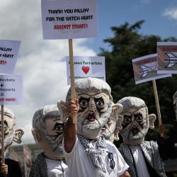 Reservistas de las Fuerzas de Defensa de Israel, con máscaras que representan a Yahya Sinwar, el jefe de Hamás en la Franja de Gaza, y con banderas palestinas, protestan frente a las oficinas de las Naciones Unidas en Ginebra. | Foto:FABRICE COFFRINI / AFP