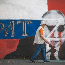 Un peatón pasa junto a un mural parcialmente vandalizado que representa al presidente ruso Vladimir Putin en Belgrado. | Foto:ANDREJ ISAKOVIC / AFP