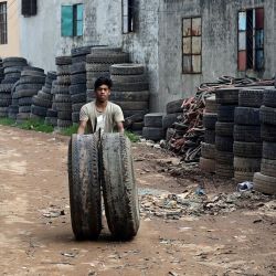 Un trabajador lleva neumáticos de camión usados para cortarlos y reutilizarlos en una instalación en Dhaka, Bangladesh. | Foto:MUNIR UZ ZAMAN / AFP