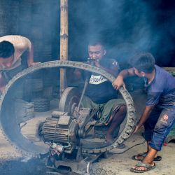Unos trabajadores utilizan una cortadora motorizada para cortar neumáticos usados en un patio de Dhaka, Bangladesh. | Foto:MUNIR UZ ZAMAN / AFP