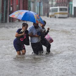 Unas personas vadean una calle inundada de La Habana, tras las fuertes lluvias caídas en la isla. - Las fuertes lluvias de los restos del huracán Agatha inundaron gran parte del oeste de Cuba la semana pasada, matando al menos a tres personas en La Habana. | Foto:YAMIL LAGE / AFP