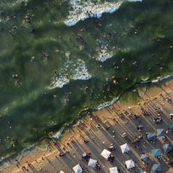 Esta imagen muestra una vista aérea de los bañistas que se reúnen a lo largo de la orilla del mar Mediterráneo en Beit Lahia, en el norte de la Franja de Gaza, mientras los estudiantes comienzan sus vacaciones de verano. | Foto:MOHAMMED ABED / AFP