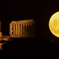 Esta fotografía muestra una luna llena, conocida como la "Luna de fresa", detrás del Templo de Poseidón en el Cabo Sounion, al sur de Atenas. | Foto:Angelos Tzortzinis / AFP