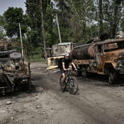 Un hombre circula con su bicicleta entre dos camiones militares destruidos en la ciudad de Lysychansk, región oriental ucraniana de Donbas. | Foto:ARIS MESSINIS / AFP