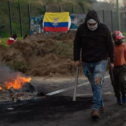 Un manifestante camina junto a una barricada durante un bloqueo en apoyo a la movilización nacional contra el gobierno ecuatoriano en la carretera Panamericana en la comuna de San Miguel del Común, en las afueras de Quito. | Foto:Verónica Lombeida / AFP