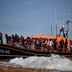 Migrantes, recogidos en el mar al intentar cruzar el Canal de la Mancha, son ayudados a desembarcar desde un bote salvavidas de la Royal National Lifeboat Institution (RNLI) en Dungeness, en la costa sureste de Inglaterra. | Foto:Ben Stansall / AFP