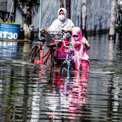 Una madre y su hija empujan sus bicicletas a través del agua de la inundación después de fuertes lluvias, en Waru, en Sidoarjo, Java Oriental, Indonesia. | Foto:Xinhua/Kurniawan
