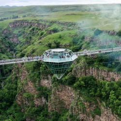 La gente asiste a la ceremonia de inauguración de un puente de cristal de 240 metros de largo sobre el cañón de Tsalka, con una cafetería en forma de diamante en el centro, a las afueras de la ciudad de Tsalka, a unos 100 km de Tiflis. | Foto:VANO SHLAMOV / AFP