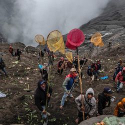 Los aldeanos utilizan redes para atrapar las ofrendas que lanzan los miembros del grupo subétnico Tengger en el cráter del volcán activo del Monte Bromo como parte del festival Yadnya Kasada en Probolinggo, provincia de Java Oriental, Indonesia. | Foto:JUNI KRISWANTO / AFP