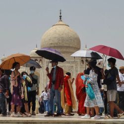 Turistas se protegen del sol bajo sombrillas mientras visitan el Taj Mahal durante un caluroso día de verano en Agra, India. | Foto:PAWAN SHARMA / AFP